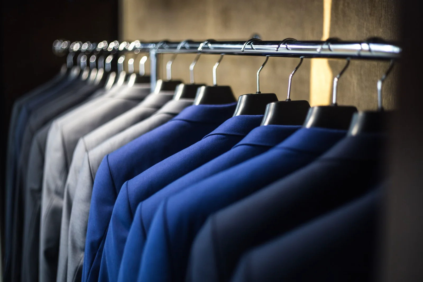Representative close view of tailored navy jackets hanging on a rack